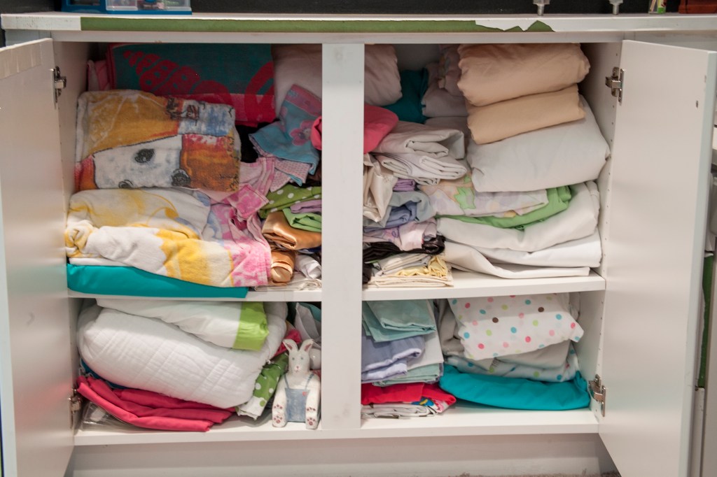 Now for the inside! Aughhhh! Right? It's been about five years since I cleaned this cabinet out. I just keep shoving stuff into it. I refolded and through out the old sheets we haven't used for years. I also packed up my older daughter's sheets for her own place. 