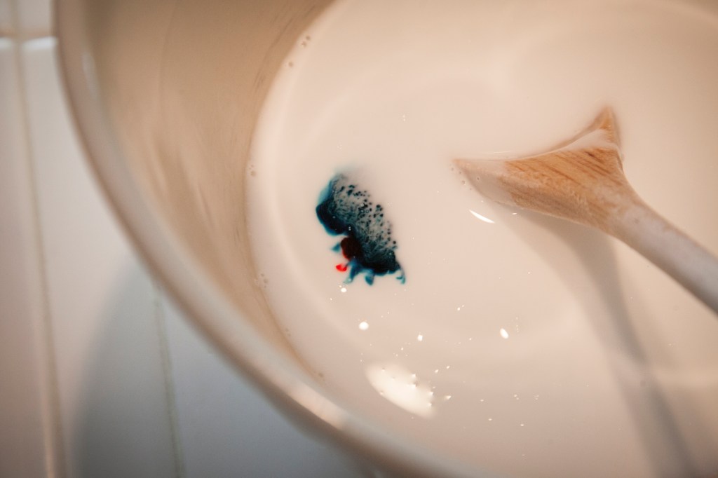 Dropping the food coloring into the glue mixture.